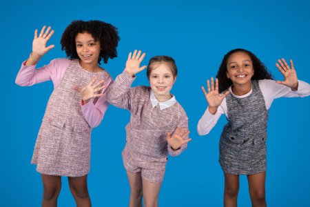 Photo for Cheerful international little girlfriends in casual dance, have fun, enjoy spare time isolated on blue background, studio. Family, friendship, study and education, art for children - Royalty Free Image