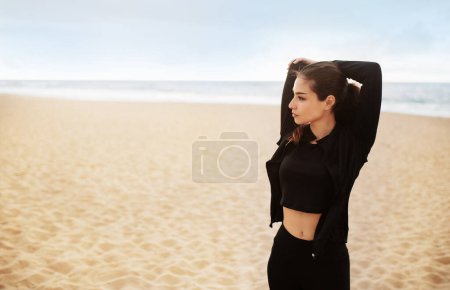 Foto de Entrenamiento al aire libre. Ajuste entrenamiento de mujer joven fuera, mujer europea deportiva estirando los músculos del brazo, preparándose para el entrenamiento de fitness o trotar en la playa - Imagen libre de derechos