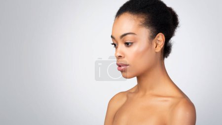 Téléchargez les photos : Bodycare Concept. Femme afro-américaine torse nu posant gracieusement à côté de l'espace de copie, mettant en valeur la beauté naturelle et l'autosoin sur fond gris. Panorama, Prise de vue studio - en image libre de droit