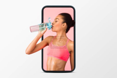 Photo for Happy young african american woman in sports bra drink water from bottle on phone screen isolated on white studio background, collage. Active lifestyle, fitness training, weight loss, health care - Royalty Free Image