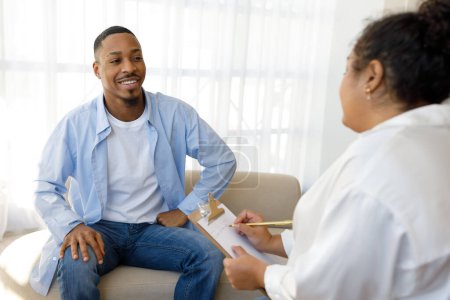 Photo for Positive happy cheerful young black guy sitting on couch against chubby lady psychotherapist, patient sharing good results of personal therapy with psychologist, copy space - Royalty Free Image