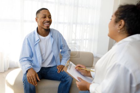 Photo for Mental health, psychological support, help concept. Cheerful handsome millennial african american guy smiling to young woman psychotherapist at clinic, thankful for successful session - Royalty Free Image