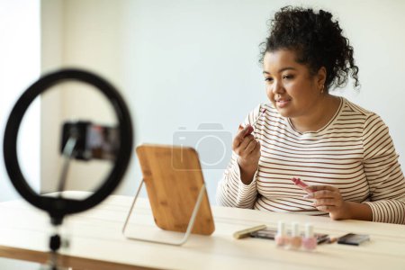 Photo for Beautiful chubby hispanic brunette young woman makeup artist applying lip gloss and streaming from home, pretty lady beauty blogger recommending nice lipstick, home interior - Royalty Free Image