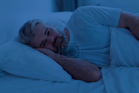 Téléchargez les photos : Réveiller insomnie bouleversé homme d'âge moyen couché seul la nuit, ne peut dormir, se sentir seul, souffrant de dépression ou d'anxiété, éprouvant des difficultés à dormir, intérieur de la maison - en image libre de droit