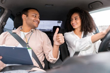 Photo for Successful Driving License Test. Instructor Man Gesturing Thumbs Up To Happy Middle Eastern Driver Woman As She Driving Sitting In Car. Passed Exam In Auto School Concept - Royalty Free Image