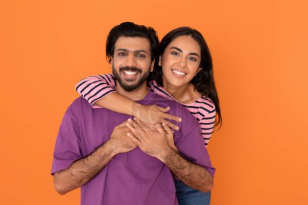 Photo for Portrait of happy cheerful beautiful sweet young indian lovers man and woman in casual hugging and smiling at camera on orange studio background. Love, affectionate, relationships concept - Royalty Free Image