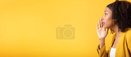 Photo for Black lady whispering secret, pressing hand to face, isolated on yellow background, side view, panorama with free space. Gossip, good news and lifestyle, surprise, ad and offer - Royalty Free Image