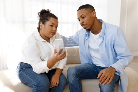 Photo for Psychological help online. Young hispanic lady plus size psychotherapist showing cell phone to her patient client millennial african american guy suffering from addiction, depression, anxiety - Royalty Free Image