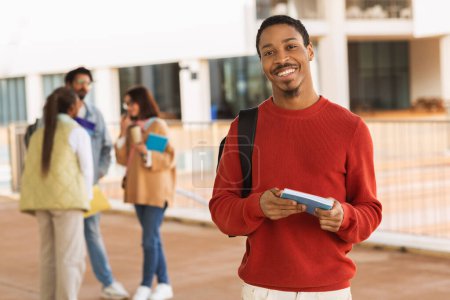 Photo for Positive millennial black man student in casual with books ready to learning, go to lesson at university outdoor. Ad and offer, break from education, knowledge and modern study - Royalty Free Image