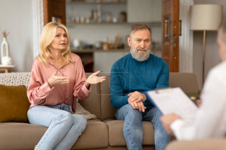 Photo for Marital Therapy. Unhappy Senior Spouses Seeking Guidance And Support From Professional Psychologist, Wife Complaining During Session Having Problems In Relationship, Sitting On Couch Indoor - Royalty Free Image