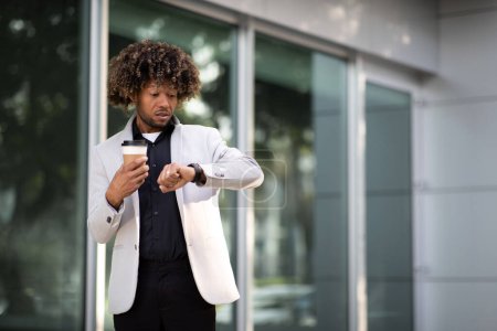 Photo for Never dont be late on business meeting. Worried black middle aged businessman looking at his watch and drinking coffee on the way to office, copy space. Business lifestyle concept - Royalty Free Image