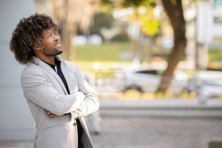 Photo for Confident middle aged african american businessman in suit standing outdoors and looking away at free space. Successful black entrepreneur man posing in suit outside - Royalty Free Image