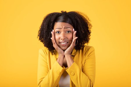 Photo for Oh no. Portrait of emotional black lady looking at camera and touching cheeks, reacting to news or offer, standing isolated over yellow studio background - Royalty Free Image