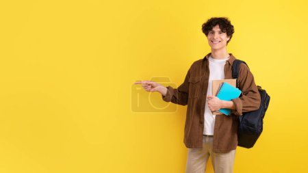 Photo for Great Education Offer. Cheerful Student Guy With Textbooks And Backpack Pointing Finger Aside At Copy Space, Advertising New Courses Over Yellow Background, Studio Shot. Panorama - Royalty Free Image