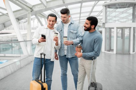 Photo for Travel Tech. Three Passengers Guys Surfing Internet On Smartphone, Using Airport Wifi To Stay Connected Traveling Together On Vacation, Standing In Departure Terminal Indoor - Royalty Free Image