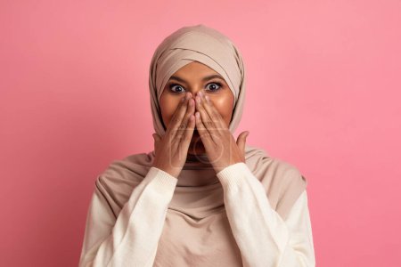 Photo for Omg. Surprised Muslim Woman In Hijab Covering Mouth With Hands In Amazement, Happy Excited Islamic Woman Emotionally Reacting To Good News, Posing Over Pink Studio Background, Copy Space - Royalty Free Image