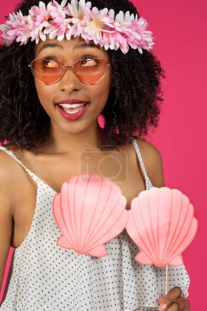 Photo for Happy surprised young black curly woman in sunglasses and wreath enjoy travel resort isolated on pink background, studio, vertical, close up. Vacation ad and offer, fun at beach party in spare time - Royalty Free Image