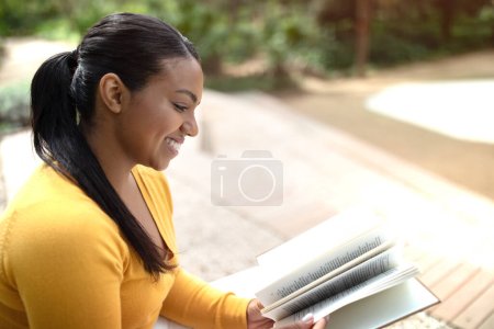 Photo for Happy brazilian lady reading book, studying alone outdoors, resting in park, free copy space. Relax, lifestyle, hobbies in free time, knowledge and education - Royalty Free Image