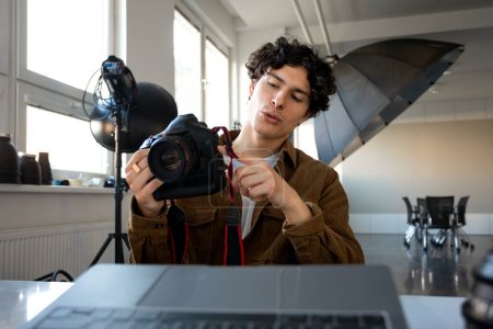 Photo for European male photographer using modern photo camera while working on laptop at workplace in studio. Professional photography and creative business career concept - Royalty Free Image