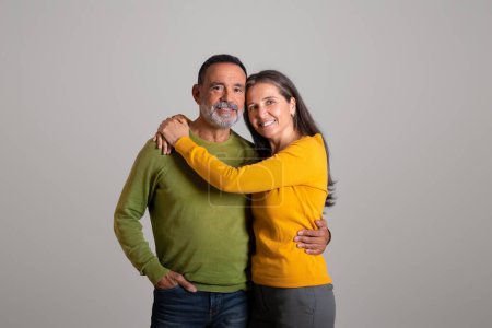 Photo for Positive cheerful caucasian retired couple hugs, enjoy date together, romance and positive lifestyle on gray studio background. Love, family relationship, ad and offer, health care - Royalty Free Image