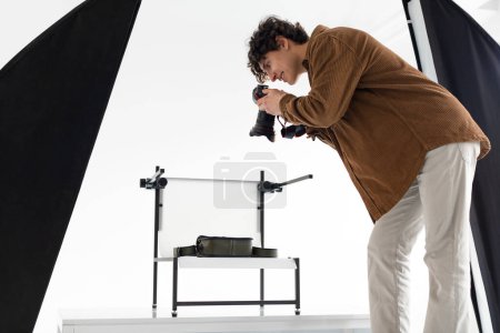 Photo for Creativity unleashed. Young photographer guy during content photoshoot, man working in photostudio with modern equipment, side view - Royalty Free Image