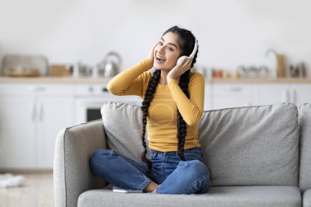 Photo for Favorite Playlist. Happy Joyful Indian Female Listening Music In Wireless Headphones At Home, Cheerful Young Eastern Woman Having Fun In Living Room, Enjoying Domestic Leisure, Copy Space - Royalty Free Image