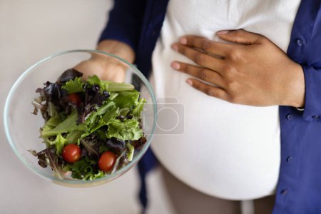 Téléchargez les photos : Millennial femme noire avec gros ventre aime la grossesse, tenir la salade, fermer, vue sur le dessus. Soins de santé, bonne nutrition, maternité végétalienne et attente de l'enfant, alimentation, cultures - en image libre de droit