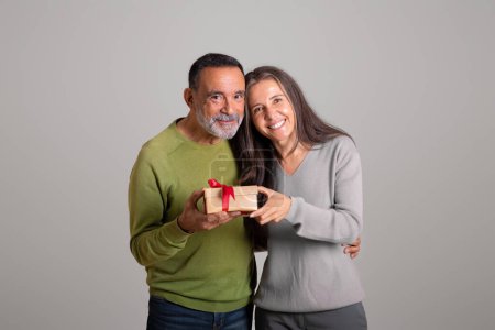 Photo for Positive caucasian aged couple box with gift, celebrating birthday, isolated on gray background, studio. Congratulations on holiday, anniversary and present on new year, Valentine day - Royalty Free Image