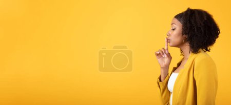 Photo for Silence, secret gesture, gossip concept. Young black curly lady holding finger near lips and making shhh sign, isolated on yellow background, profile, panorama with copy space - Royalty Free Image