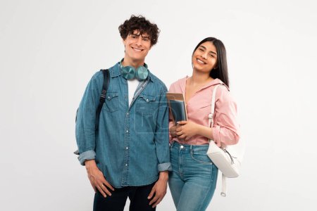 Photo for Youth And Friendship. Happy Students Couple Posing With Backpack And Textbooks Smiling To Camera Hugging Over White Studio Background. Shot Of Cheerful College Friends Duo - Royalty Free Image