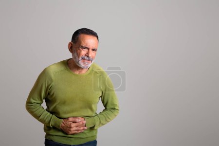 Photo for Sad despaired caucasian aged man in casual suffering from pain in stomach, belly, ulcer isolated on gray background, studio. Health problems, diarrhea, bloating and gastritis - Royalty Free Image