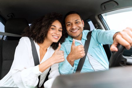 Foto de Joyful Middle Eastern Couple In Car Gesturing Thumbs Up Aprobando su nuevo vehículo posando en el interior, sonriendo a la cámara. Gran oferta de concesionario de automóviles. Nos gusta el viaje en concepto de automóvil - Imagen libre de derechos