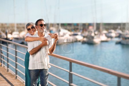 Photo for Seaside Love. Senior Married Couple Embracing Posing At Marina Dock With Sailboats, Looking Aside At Free Space, Advertising Yacht Cruise, Enjoying Sunny Day By The Sea Outside - Royalty Free Image