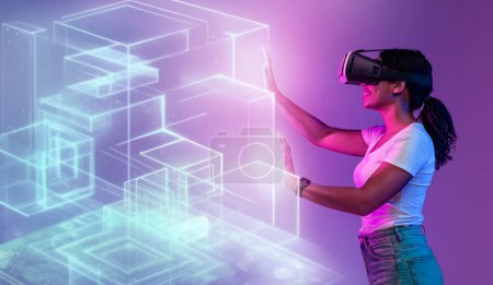 Photo for Touch to future. Young positive black woman in vr headset touching glowing virtual holographic cubes, enjoying modern technologies and futuristic abilities over purple background - Royalty Free Image