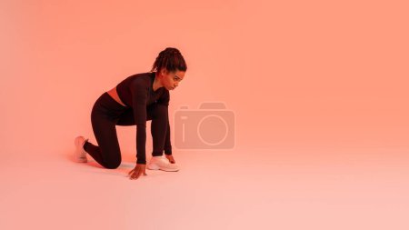 Photo for Strong and fit. Sporty black runner woman doing crouch start looking at free space over red neon studio background, panorama. Sport motivation concept - Royalty Free Image
