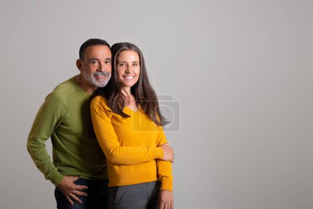 Photo for Happy cheerful european elderly husband hugging woman, enjoy date together on gray studio background. Positive lifestyle, family relationship, romance and health care, life insurance - Royalty Free Image