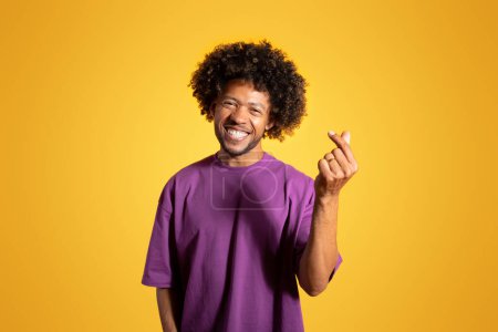Photo for Glad confident mature black curly man in violet t-shirt snaps fingers gesture isolated on yellow background, studio. Lifestyle, great deal, recommendation, ad and offer, good creative idea - Royalty Free Image