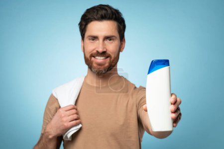 Photo for Happy middle aged bearded man showing blank shampoo bottle to camera and smiling, standing over blue background, mockup. Haircare and bodycare cosmetics concept - Royalty Free Image