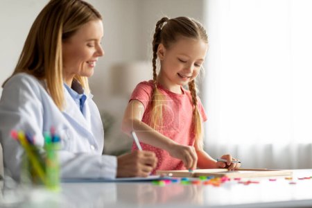Photo for Art Therapy For Kids. Cute Little Girl Painting On Draw Board During Meeting With Child Development Specialist, Therapist Lady Observing Kid Patient Making Learning Activities, Closeup - Royalty Free Image