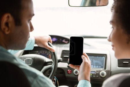 Photo for Travel Planning App. Arabic Spouses Using Phone In Car Browsing Trip Destinations And Short Routes Sitting Inside Vehicle. Back View, Selective Focus On Smartphone Screen. Mockup - Royalty Free Image
