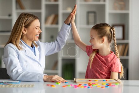 Photo for Development specialist and child giving high five, celebrating successful therapy session, smiling therapist lady joining hands with cute little girl, cheering progress and achievements in lessons - Royalty Free Image