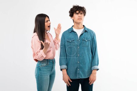Photo for Problematic Relationship. Emotional Girlfriend Shouting At Boyfriend Having Quarrel Standing On White Background. Studio Shot Of Unhappy Young Couple Having Conflicts. Disagreement And Breakup - Royalty Free Image