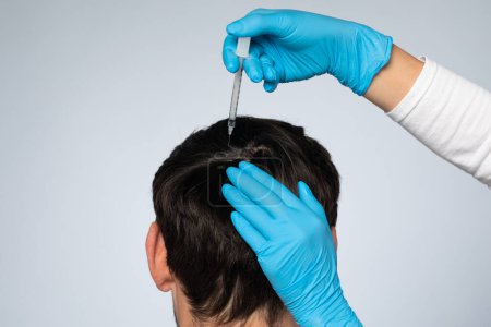 Photo for Mesotherapy concept. Unrecognizable man receiving injections in his head, having mesotherapy session at beauty salon, therapist in protective glove with syringe, back view - Royalty Free Image