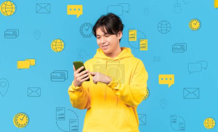 Photo for Smiling young asian man with phone in hand posing over diverse digital world icons on blue background. Collage for modern technologies, money transfer, banking, online payments concept, mobile app - Royalty Free Image