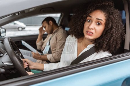 Photo for Fear Of Driving. Scared Driver Lady Looking At Camera Through Car Window, Being Afraid Of Test With Professional Instructor Sitting In Auto. Nervous Learner At Failed Exam Concept. Selective Focus - Royalty Free Image