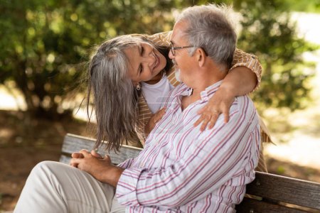 Photo for Happy senior woman hugging man in casual, sit on bench, enjoy walk together in park outdoor. Love relationships, retirement, free time and weekend, lifestyle and date, ad, offer - Royalty Free Image