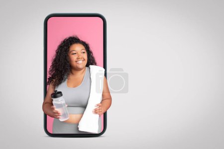 Photo for Positive black oversize woman in sportswear with bottle of water on smartphone screen on grey studio background, collage, free space. Fit blog, workout, weight loss and health care - Royalty Free Image