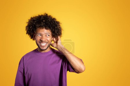 Téléchargez les photos : Heureux coûteux homme bouclé noir mature en violet t-shirt pensée et tête à gratter, isolé sur fond jaune, studio. Mode de vie, choix, émotions humaines, résolution de problèmes, publicité et offre - en image libre de droit
