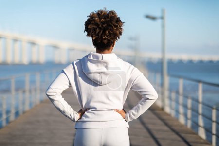 Photo for Sport Motivation. Unrecognizable Black Female In Sportwear Standing Outdoors On Wooden Pier, African American Athletic Woman Ready For Jogging Or Fitness Training Outside, Rear View, Copy Space - Royalty Free Image