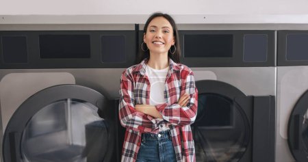 Photo for Self-Service Laundry. Happy Young Woman Posing Near Washing Machines Standing Smiling To Camera Indoors. Lady Washes Her Clothes Advertising Offer At Public Laundrette Service. Panorama - Royalty Free Image